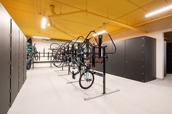 Bicycle storage and large metal lockers for storage. Bright yellow ceiling and white floor.